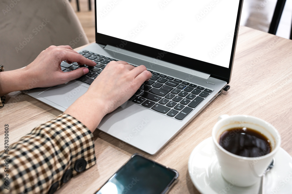 Hands of a girl typing text on a laptop. The girl works at a laptop and drinks coffee in a cafe. Selective focus. Hands of a girl typing text on a laptop. The girl works at a laptop and drinks coffee in a cafe. Selective focus.