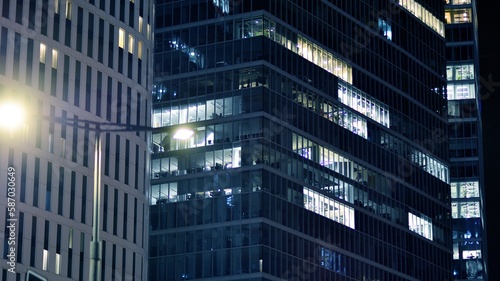 Pattern of office buildings windows illuminated at night. Glass architecture  corporate building at night - business concept. Blue graphic filter.