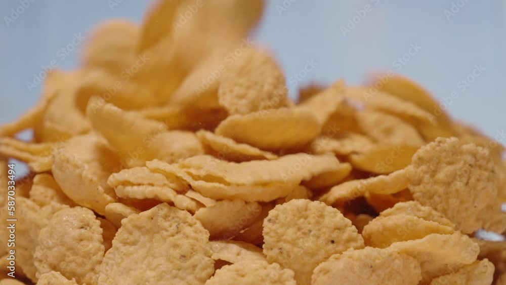 Corn flakes fall against the blue sky and fill the entire space. Close-up. Slow motion. Corn flakes fall against the blue sky and fill the entire space. Close-up. Slow motion.
