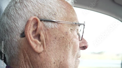 video of retired old man in his eighties driving, video of co-driver to driver, serious man with glasses and headphones, serious man watching the road photo