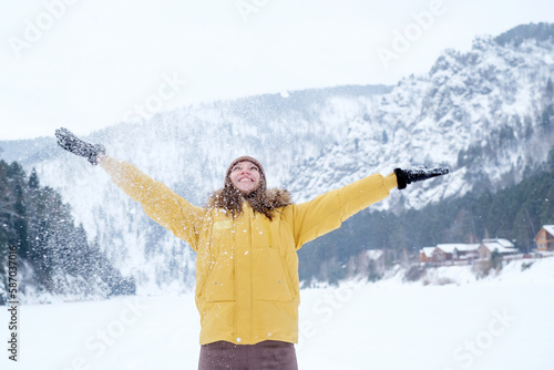 Beauty Girl smile in  winter mountains Outdoor. Flying Snowflakes.  Beauty young woman Having Fun in Winter Park. Good mood while spending time outdoors on snowy winter day in mountains
