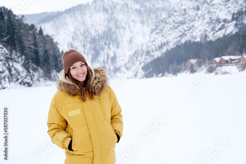 Beauty Girl smile in winter mountains Outdoor. Flying Snowflakes. Beauty young woman Having Fun in Winter Park. Good mood while spending time outdoors on snowy winter day in mountains