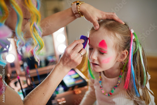 Artist painting little preschooler girl like unicorn on a birthday party