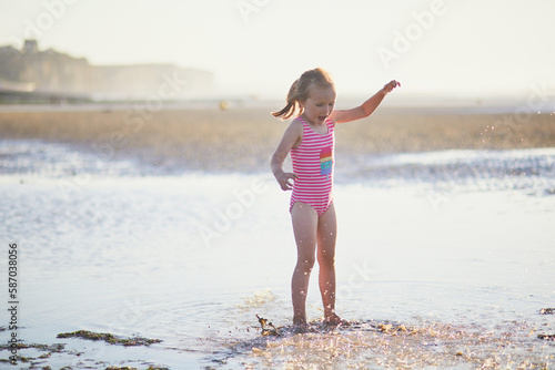Preschooler girl having fun on the sand beach at Atlantic coast of Normandy, France