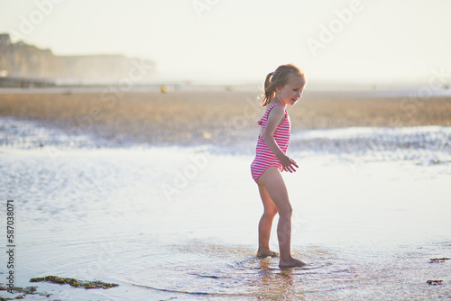 Preschooler girl having fun on the sand beach at Atlantic coast of Normandy, France