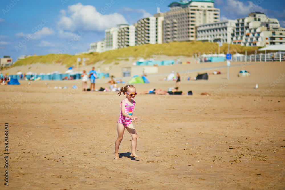 Preschooler girl having fun on the sand beach at sea coast in Noordwijk, the Netherlands Preschooler girl having fun on the sand beach at sea coast in Noordwijk, the Netherlands