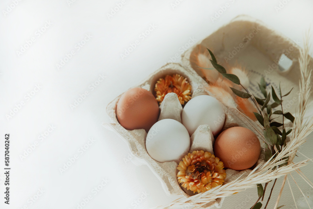 Easter white and brown eggs in a basket with flowers on a white background Easter white and brown eggs in a basket with flowers on a white background