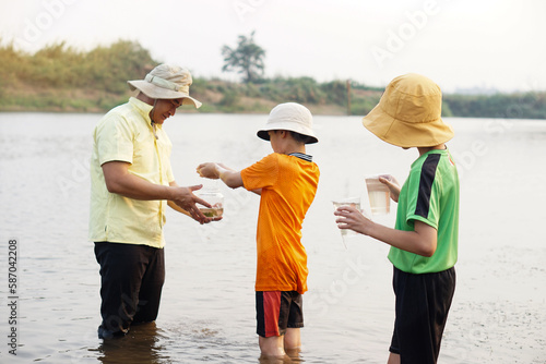 Asian man teacher and students are exploring water from nature source. Concept, Ecology and environment study. Outdoor summer camp activity. Education. Learning by doing. Life experience. 