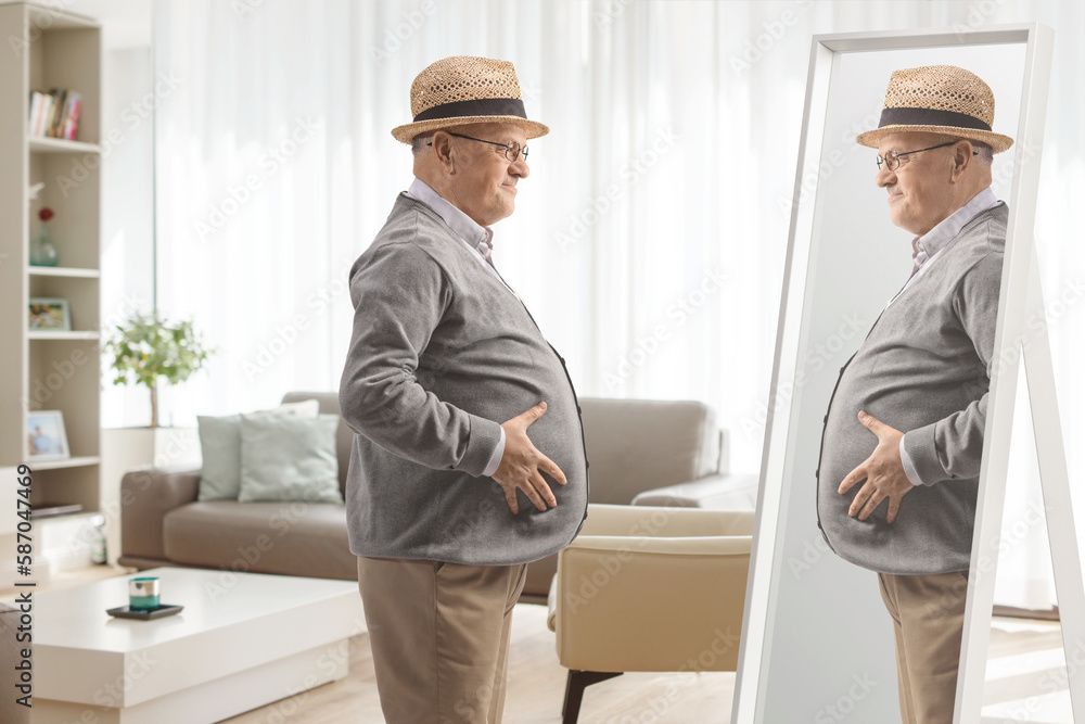 Elderly man with a big belly looking at a mirror at home Elderly man with a big belly looking at a mirror at home