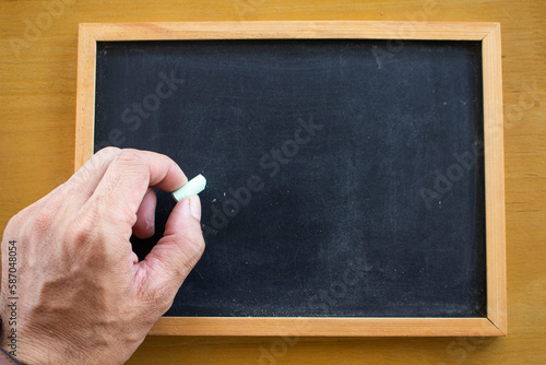 Hand writing on blackboard with chalk on wooden background, education concept