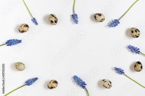 Easter quial eggs and fresh spring flowers frame. White textile background. Happy easter concept, top view, space for text. photo