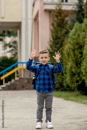 Cheerful mischievous schoolboy in blue shirt posing showing gesture. Back to school.