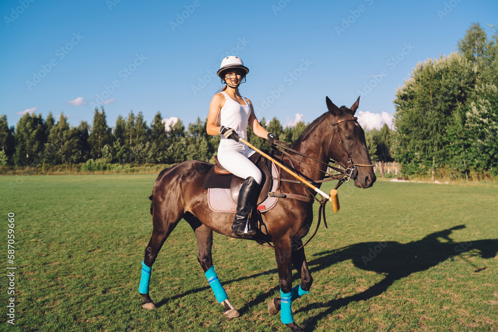 Graceful female polo player riding horse on field under blue sky Graceful female polo player riding horse on field under blue sky