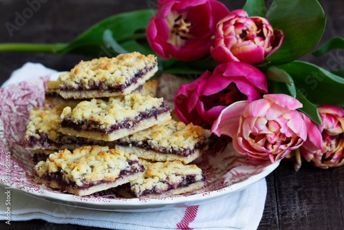 Obraz na płótnie Streusel pie with currant and rose petal filling on a background of tulips. w salonie