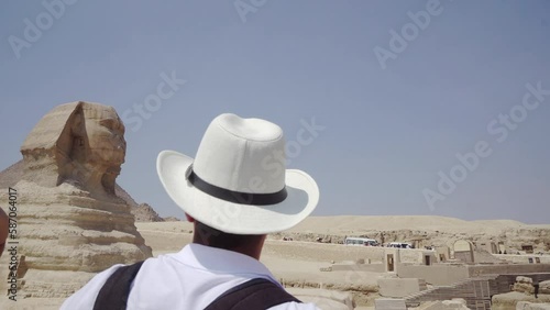 Man with straw hat visiting the Giza Pyramids and the stone Sphinx on the Giza platou in Sahara desert - the Greatest wonder of the world as part of ancient Egypt in Cairo photo