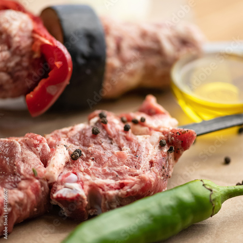 Raw kebab and kebab with vegetables on skewers. Skewers with meat, spices and vegetables for marinade on parchment paper. Light brown background. View from above. Soft focus. Close-up.