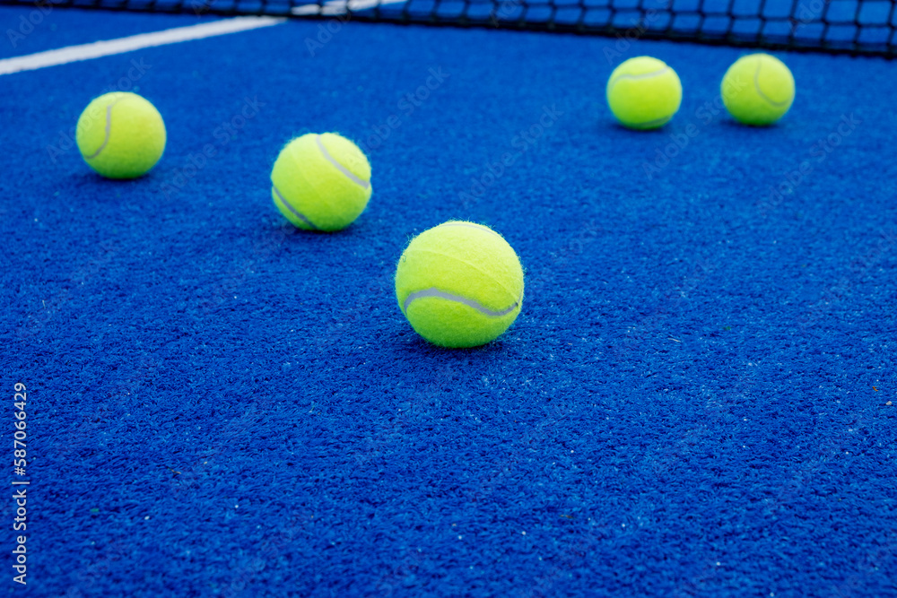 selective focus, several balls on the surface of a blue paddle tennis court
