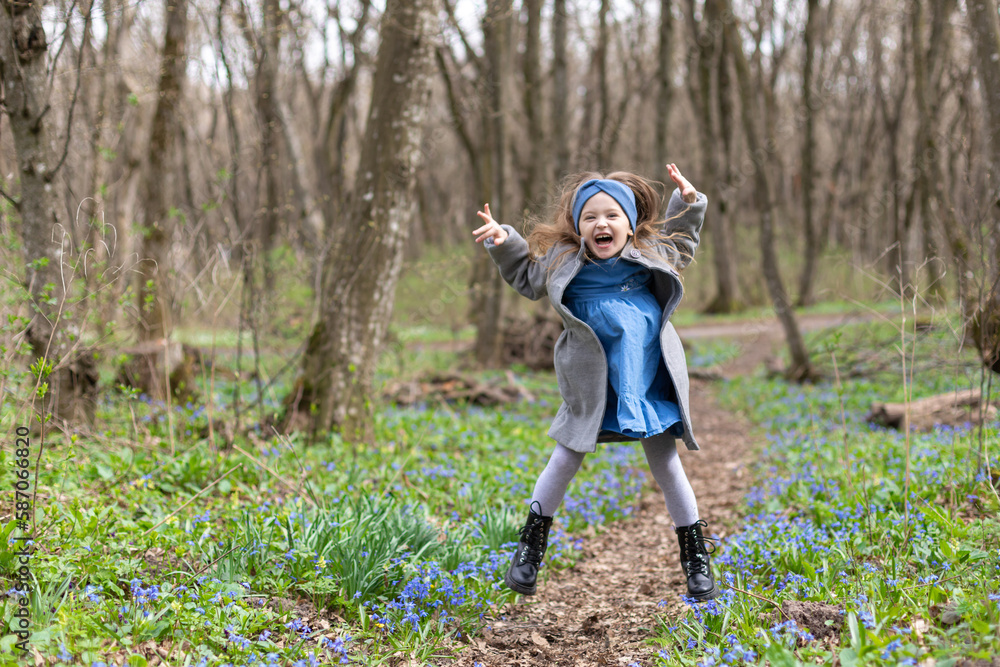 A girl is jumping on a path in the woods