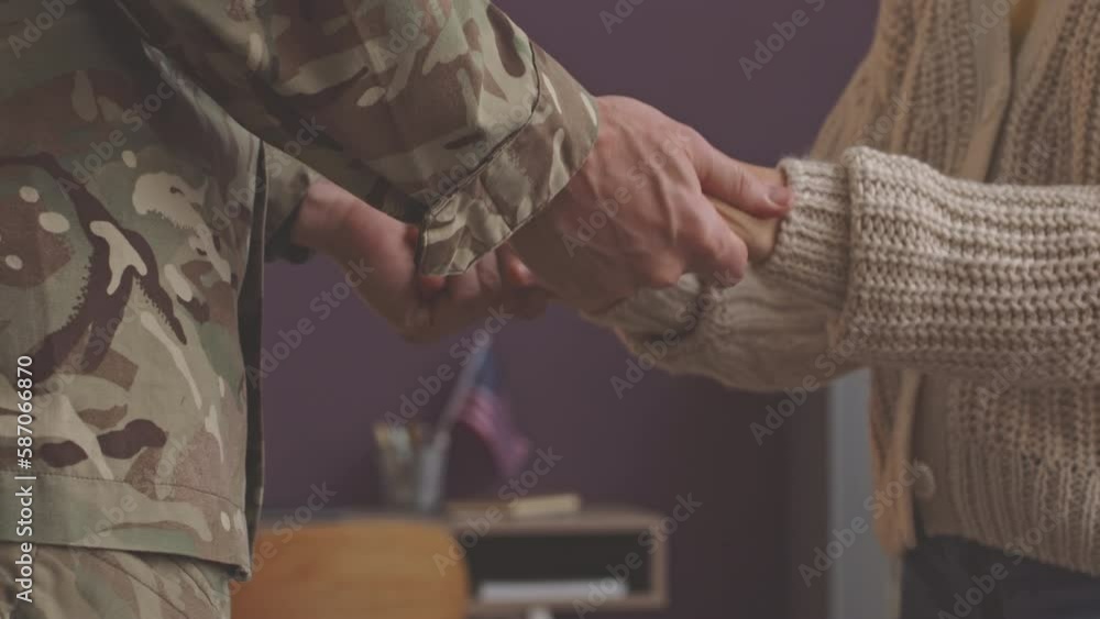 Closeup of unrecognizable soldier in military uniform holding hands of ...
