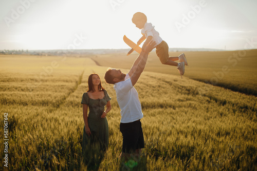 Happy family father and mother and child son walking on nature at sunset © Катя Іваськевич