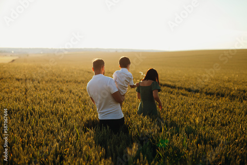 Happy family father and mother and child son walking on nature at sunset