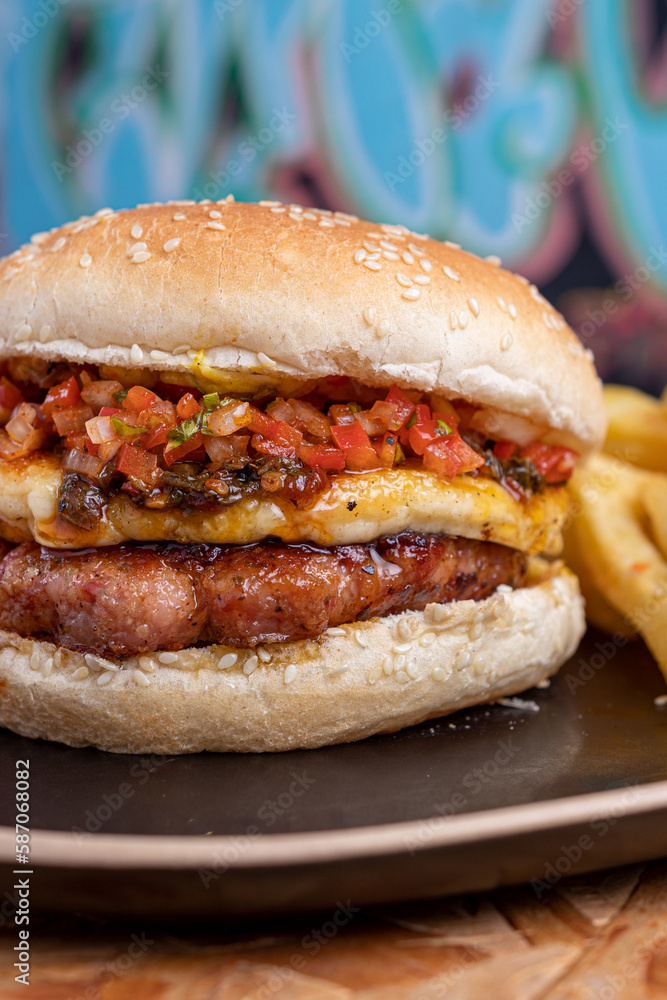 Hamburguesa con papas fritas en plato ovalado negro sobre fondo de madera Hamburguesa con papas fritas en plato ovalado negro sobre fondo de madera