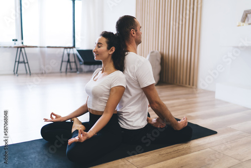 Positive diverse couple practicing yoga together in studio