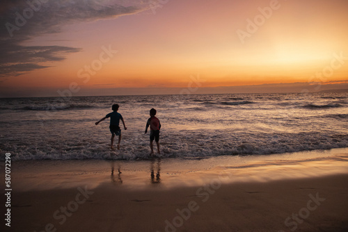 Niños felices jugando y brincando en la playa durante la puesta de sol en Puerto Vallarta México