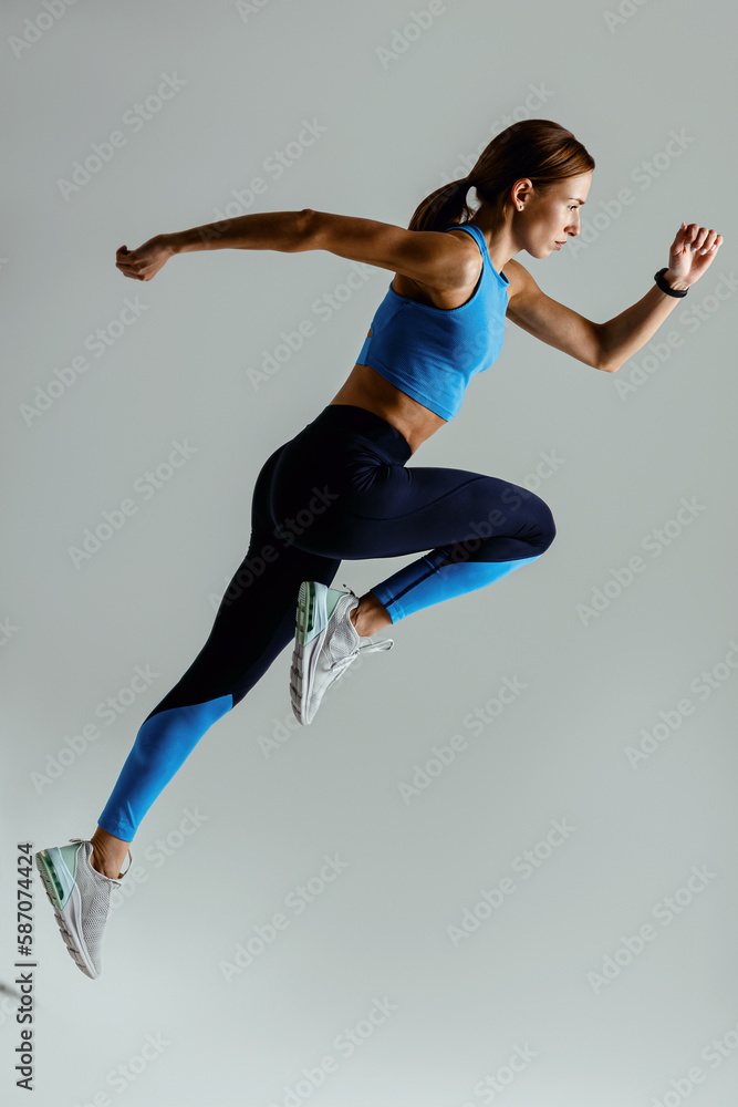 Woman running in Mid-Air exercising during cardio workout over studio background. High quality photo - obrazy, fototapety, plakaty 