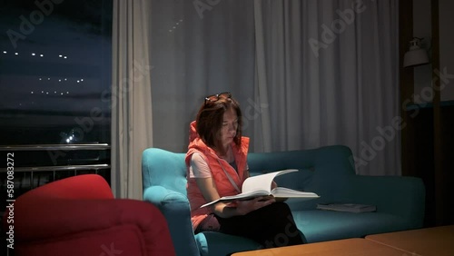 Woman reading a book siiting on sofa at night. 4k footage UHD 3840x2160  photo