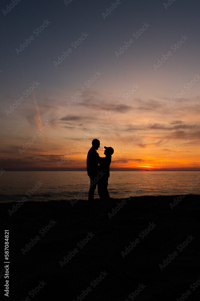 Young couple, posing backlit in a sunset on the beach