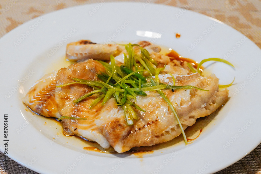 Steamed fish in black bean sauce arranged in a white plate Steamed fish in black bean sauce arranged in a white plate