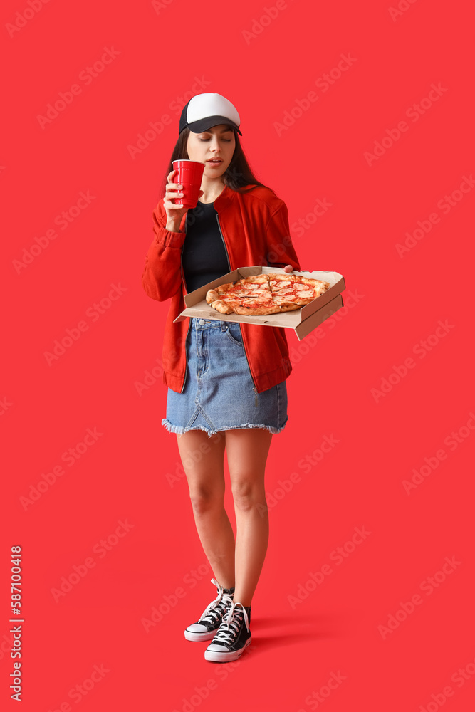 Young woman with box of tasty pizza and cup on red background Young woman with box of tasty pizza and cup on red background