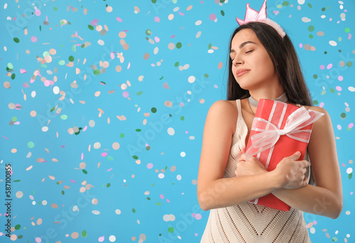 Happy young woman with Birthday gift on blue background