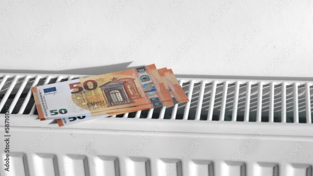 Female hand putting euro cash money banknotes on central heating radiator warming expensive cost Female hand putting euro cash money banknotes on central heating radiator warming expensive cost