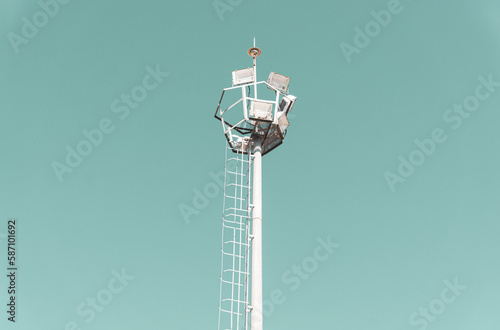 Street lighting pole isolated on turquoise sky background. Steel or metal tall illumination pole structure. Large copy space for ad or advertisement text. 