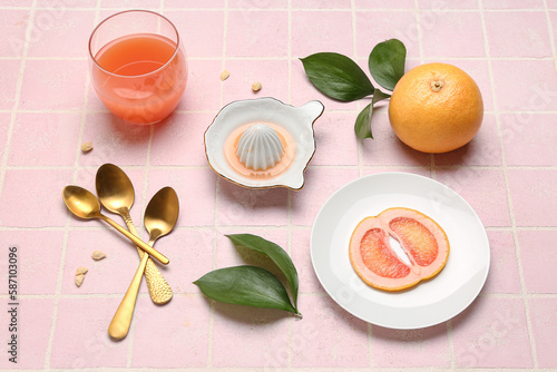Composition with ripe grapefruit, glass of juice and plant leaves on color tile background