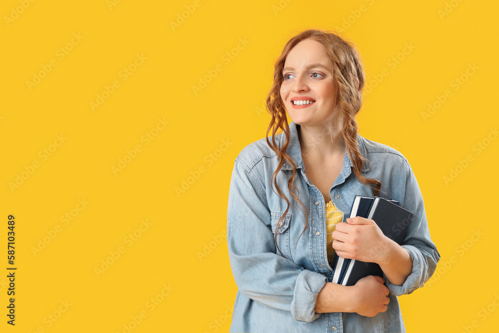 Beautiful redhead woman with books on yellow background Beautiful redhead woman with books on yellow background
