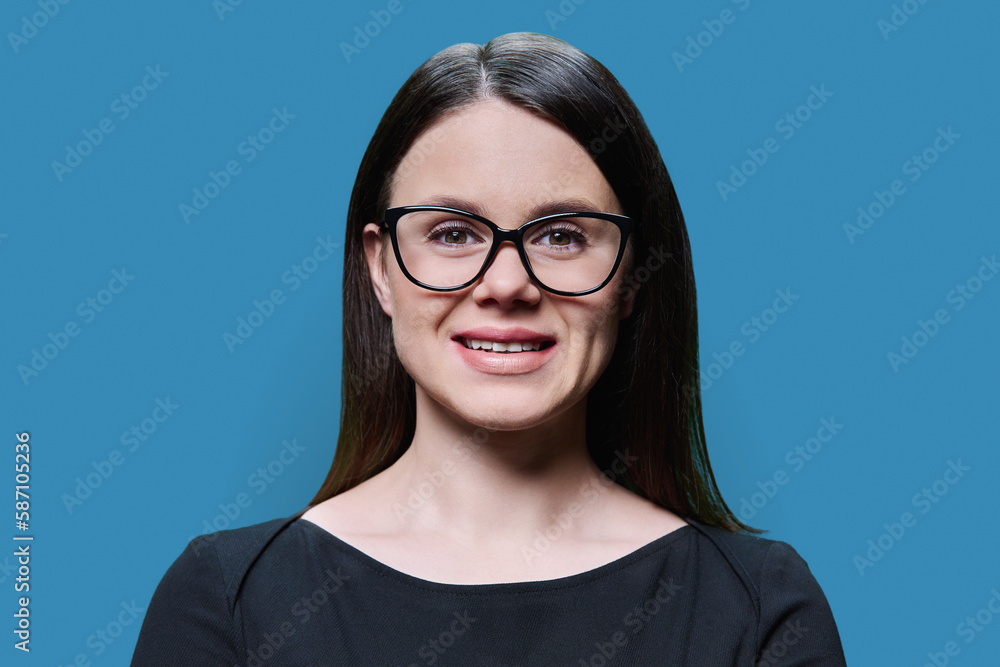 Young woman in black with glasses posing on blue background Young woman in black with glasses posing on blue background