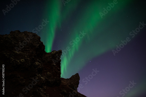 Aurora borealis beaming from a head shaped rock, Iceland