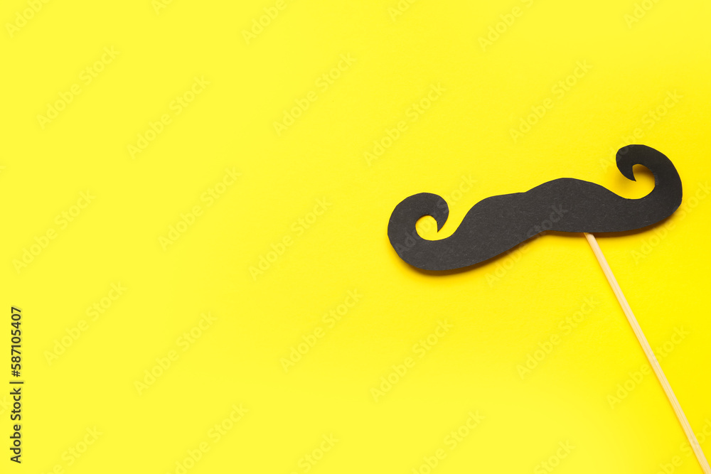 Obraz premium Wooden stick with paper mustache on yellow background