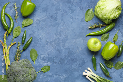 Frame made of different green vegetables on blue grunge background