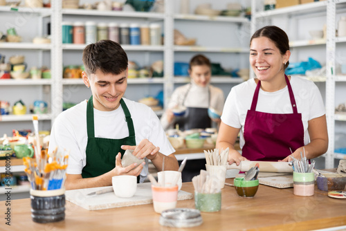 Young woman and young man sculpting ceramic product in workshop