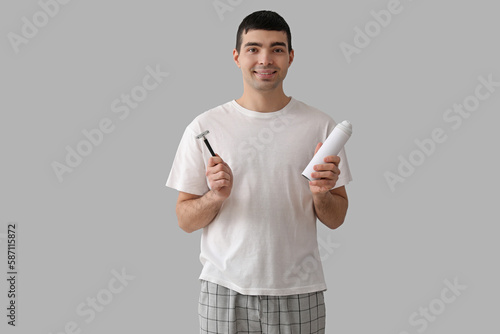 Young man with shaving foam and razor on light background