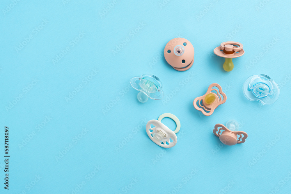 Many baby pacifiers on blue background with copy space, top view of soothers, flat lay Many baby pacifiers on blue background with copy space, top view of soothers, flat lay