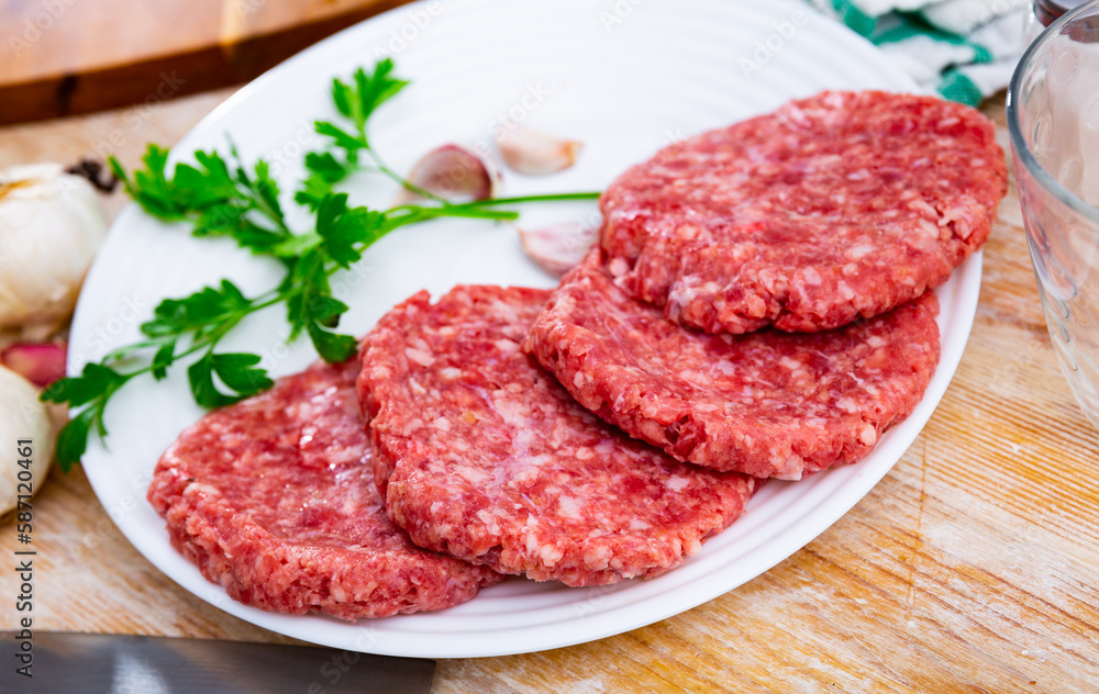 Cooking ingredients, raw burger cutlets on wooden board