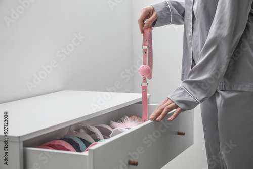 Woman taking mouth gag from open drawer in bedroom, closeup