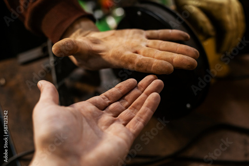 Dirty and clean hands. A Hardworking mechanics hand and white clean hand of a client. car workchop. Auto repair shop.
