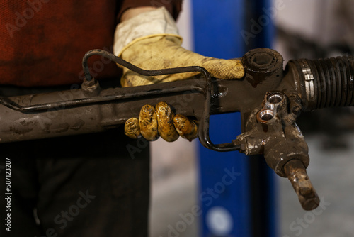 Close up of a just-removed old broken steering rack in a mechanics hands.