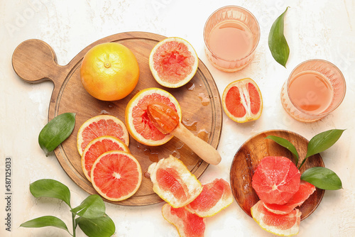 Composition with ripe grapefruit pieces and glasses of juice on light background
